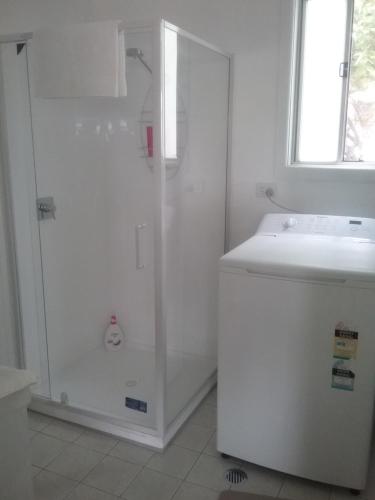 a white bathroom with a shower and a sink at Langley Cottage B&B in Coonabarabran