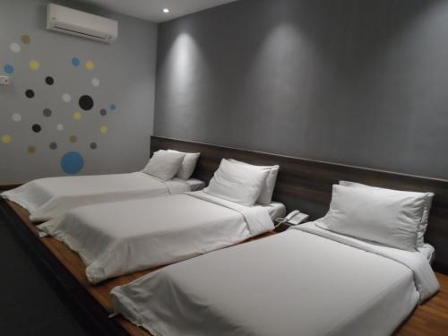 two beds with white sheets and pillows in a room at JS Hotel in Johor Bahru