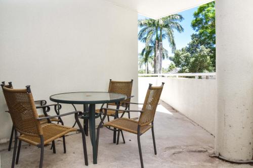 patio ze stołem, krzesłami i palmą w obiekcie Founda Gardens Apartments w mieście Brisbane