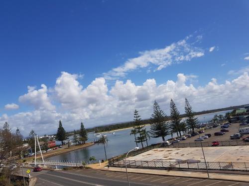 a view of a river and a parking lot with cars at Palm Court Motor Inn in Port Macquarie