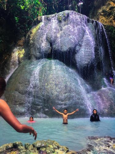 three people in the water in front of a waterfall at MLK Bamboo Beachhouse in Alegria