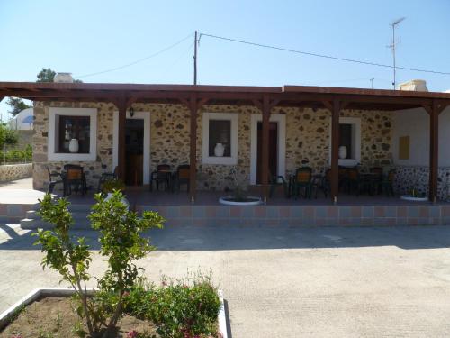a stone building with a porch with tables and chairs at Paraschos Studios Kos in Kardamaina
