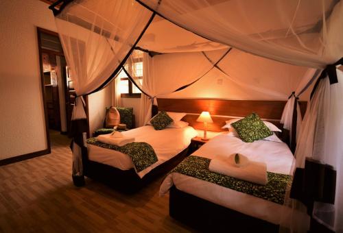 a bedroom with two beds in a tent at Elementis Entebbe in Entebbe