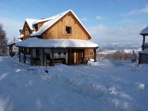a wooden house with snow on the roof at Widokowa Osada in Międzylesie