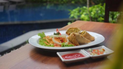 a plate of food sitting on a wooden table at Suris Boutique Hotel in Kuta
