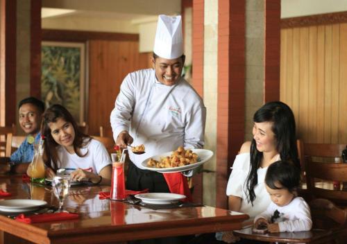 uno chef che serve cibo a un gruppo di persone a un tavolo di Kusuma Agrowisata Resort & Convention a Batu