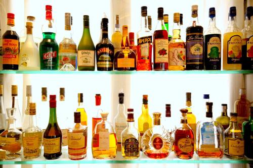 a shelf filled with lots of bottles of alcohol at Hotel Royal Bon Repos in Sainte-Maxime