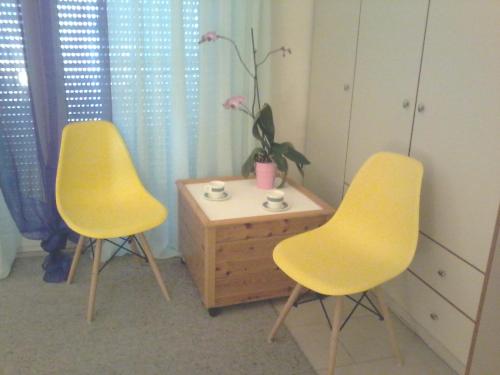 two yellow chairs and a table in a room at Persephone's Project in Heraklio