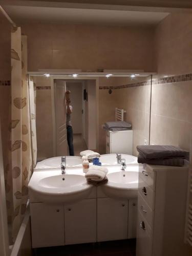 une femme prenant une photo d'une salle de bains avec deux lavabos dans l'établissement ROYAL CANNES APPARTEMENT, à Cannes