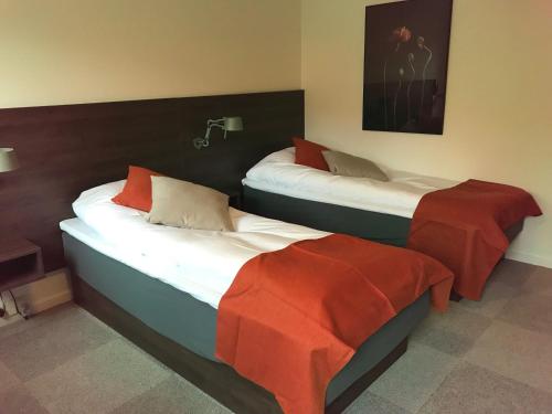 two beds in a hotel room with red sheets at Montra Odder Parkhotel in Odder