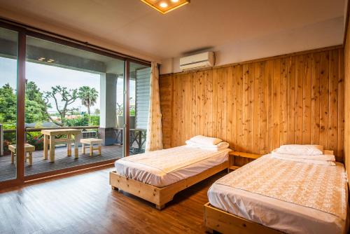 a bedroom with two beds and a balcony at Galeum Guesthouse in Seogwipo