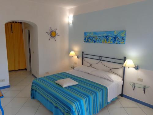 1 dormitorio con 1 cama con manta a rayas y 2 lámparas en Il Mediterraneo - Adults Only, en Ponza