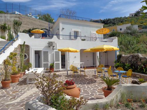 Casa blanca con sombrillas amarillas, mesas y sillas en Il Mediterraneo - Adults Only, en Ponza