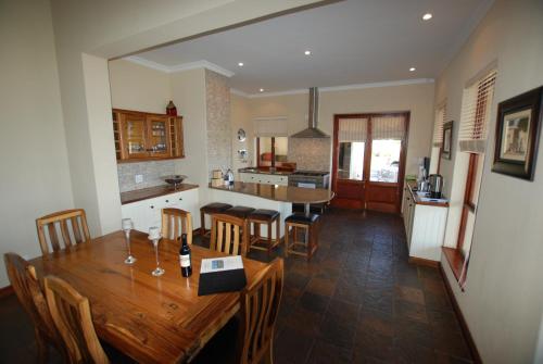 
a kitchen with a table, chairs and a refrigerator at Kingsbury Cottage in Breerivier
