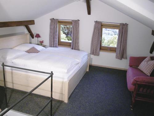 a bedroom with a bed and a chair and two windows at Rostalm in Berchtesgaden