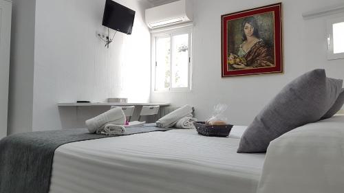 a bedroom with a white bed with a painting on the wall at Casa Botes in Cuenca