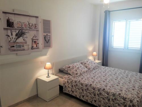 a white bedroom with a bed and two lamps at Casa Leli in Candelaria