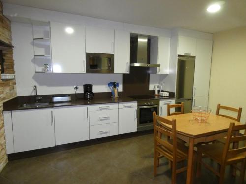 a kitchen with white cabinets and a wooden table at Vivienda de uso turístico, A Casa Do Campo in Fisterra