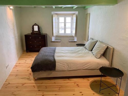 a bedroom with a bed and a window and a chair at Casa do Castelo in Castelo de Vide