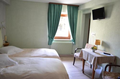1 dormitorio con cama, mesa y ventana en Logis Hotel Les Vosges en Dabo