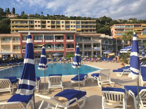 une piscine avec chaises et parasols devant un hôtel dans l'établissement Nyrenoverad lägenhet med havsutsikt, à Villefranche-sur-Mer