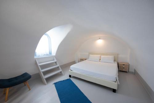 a white bedroom with a bed and a window at Red Stone Villa in Oia