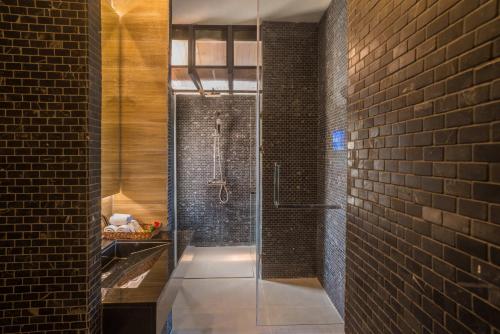 a bathroom with a glass shower in a brick wall at The Bay Samui in Choeng Mon Beach