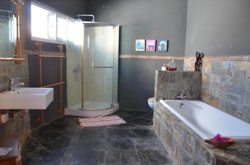 a bathroom with a tub and a shower and a toilet at serin du cap in Blue Bay