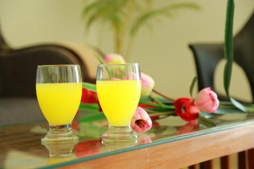 two glasses of orange juice on a table with flowers at Palmtree Leaf, Munnar in Munnar