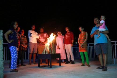 a group of people standing around a table with a fire at Palmtree Leaf, Munnar in Munnar