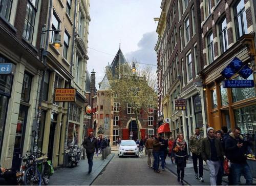 a group of people walking down a street with buildings at Facade Hotel Amsterdam in Amsterdam