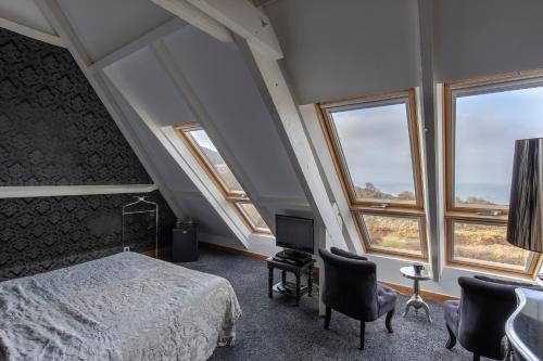 a bedroom with a bed and two chairs and windows at Domaine du Grand Bec in Villerville