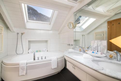 a bathroom with two sinks and a tub and a window at Boutique Hotel Albana Real - Restaurants & Spa in Zermatt