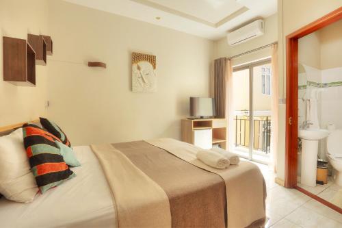 a bedroom with a bed and a bathroom with a window at L'Oiseau de L'Ocean Tourist Residence in Flic-en-Flac