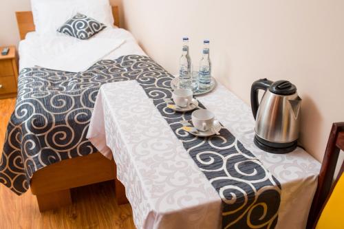 a bed with a table with two cups and a table cloth at Nad Bugiem in Hrubieszów