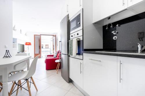 a kitchen with white cabinets and a white table at Apartamento 1º de Maio in Tavira