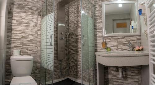 een badkamer met een toilet, een wastafel en een spiegel bij Aklidi Hotel in Mytilini