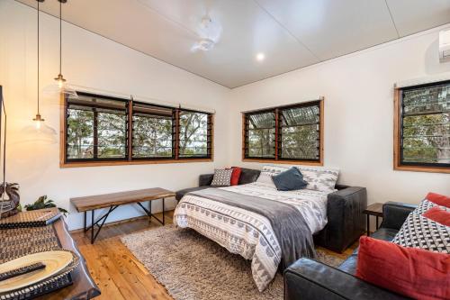 a bedroom with a bed and a couch and windows at Little Mountain Retreat in Caloundra