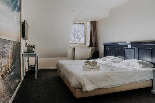 a hotel room with a bed with towels on it at Hotel De4dames in Schiermonnikoog