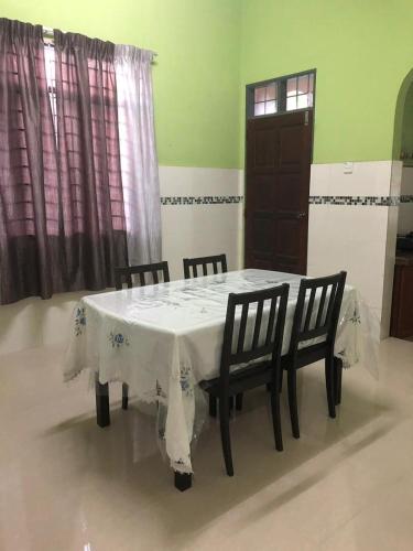 stół jadalny z 2 krzesłami i białą tkaniną w obiekcie afza homestay Sura free unifi w mieście Kampong Sura Masjid