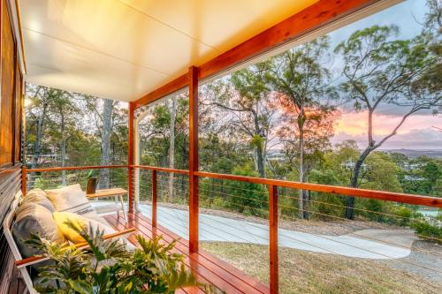 a room with a balcony with a couch and a view at Little Mountain Retreat in Caloundra