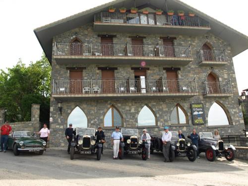 a group of people standing in front of a building with cars at El Churrón in Larrés