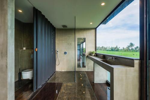 a bathroom with a sink and a toilet and a window at Kontiki Villa - Joshua District in Tabanan