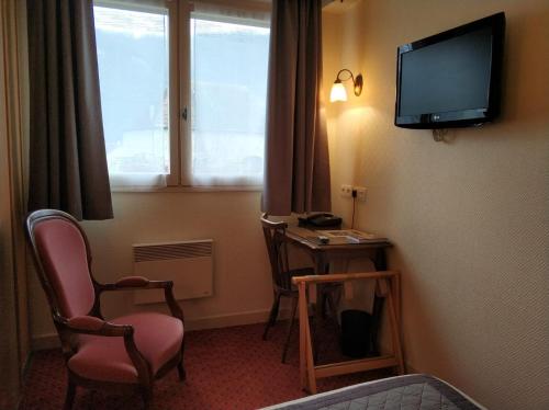 a room with a tv and a desk and a chair at Logis Hotel Calisola Besançon - Soirée Etape in Chalezeule