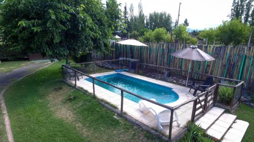 a swimming pool in a yard next to a fence at Cabañas Viña Aliwen in Vistalba