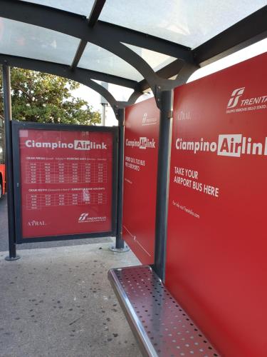 a bench at a bus stop with a red wall at Il Posto Giusto in Ciampino