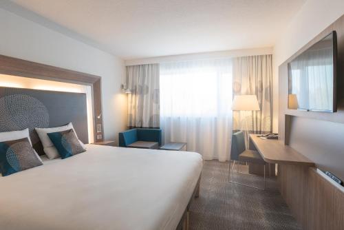 a hotel room with a large bed and a desk at Novotel Chartres in Chartres
