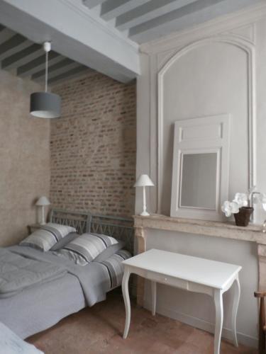 a bedroom with a large bed and a white table at Le Logis XVIIème in Moulins