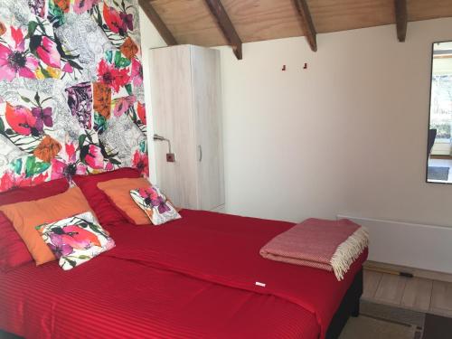 um quarto com uma cama vermelha e uma parede floral em Klein Vreugderijk em Zwolle