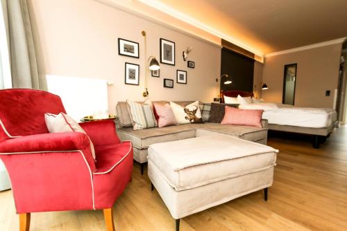 a living room with a couch and chairs and a bed at Nordseehotel Kröger in Langeoog